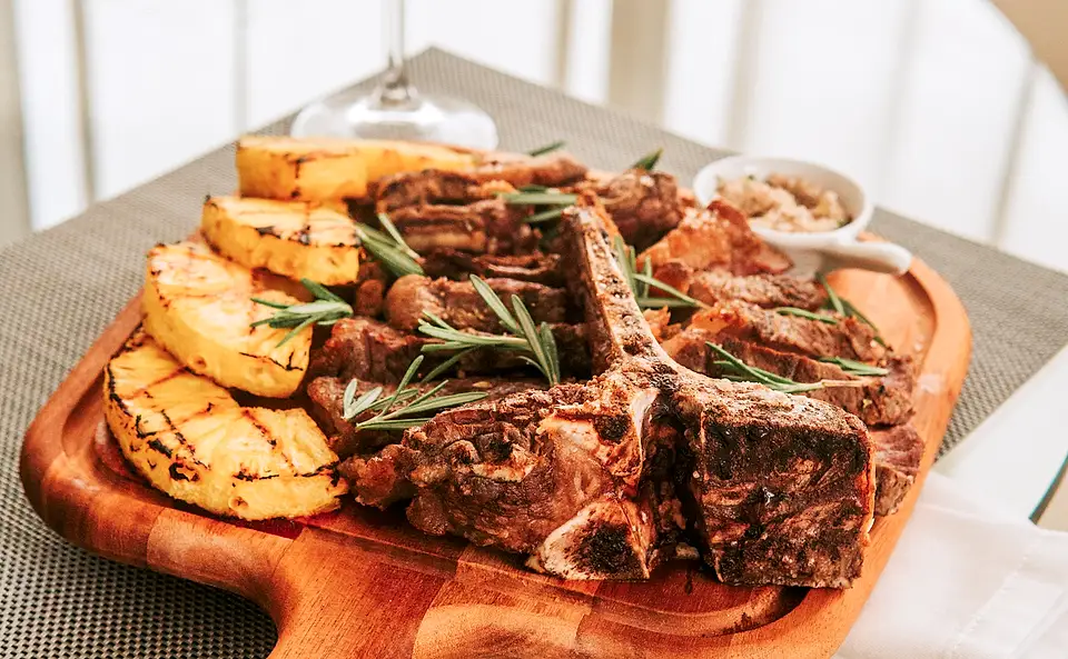 T-bone de maturação fatiado na tábua com alecrim e ananás grelhado